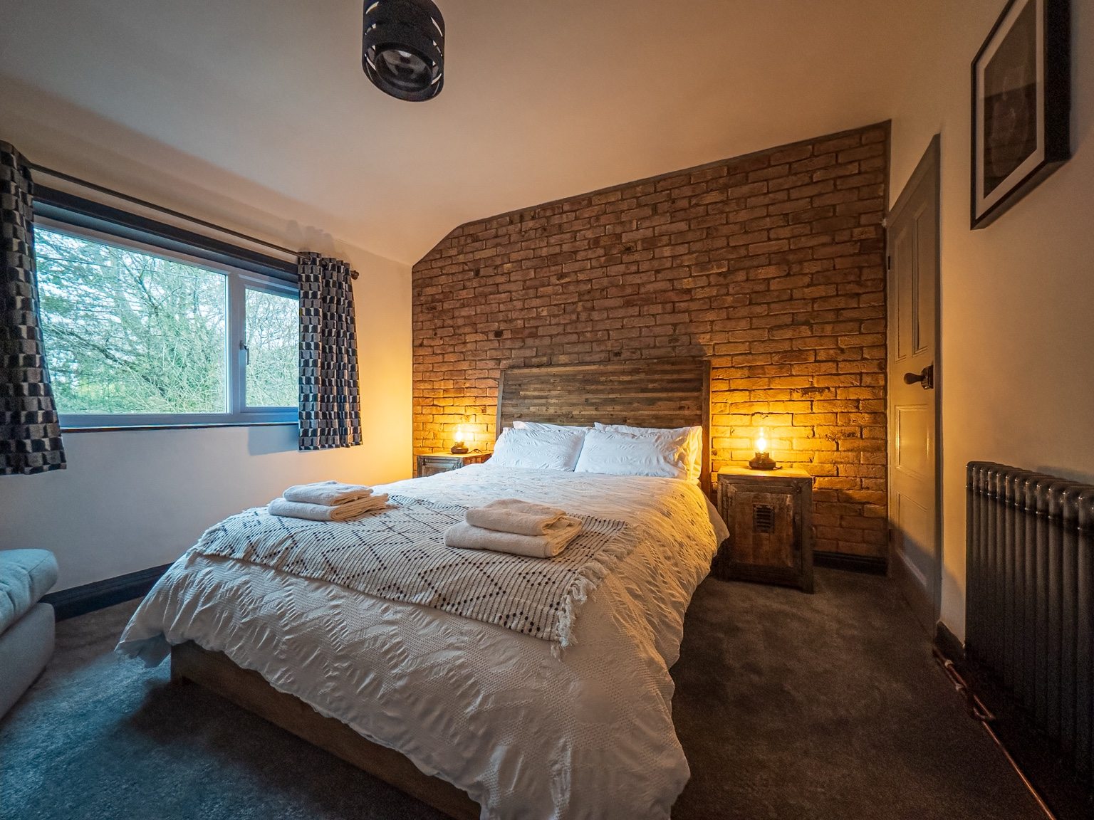 Main bedroom with exposed brick wall and warm bedside lighting